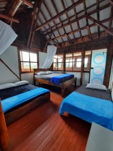twee bedden in een kamer met houten vloeren en ramen bij Hospedaje CLUB CEAN a orilla del Lago Calima in Club Las Anonimos