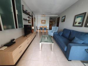 ein Wohnzimmer mit einem blauen Sofa und einem Tisch in der Unterkunft Apartamento en Sueños de Denia III muy cerca de la playa y del pueblo in Denia