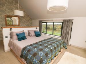 um quarto com uma cama e uma grande janela em Cae Du em Llanfairpwllgwyngyll
