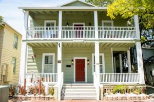 a green house with a red door and white porch at Pomar House in St. Augustine