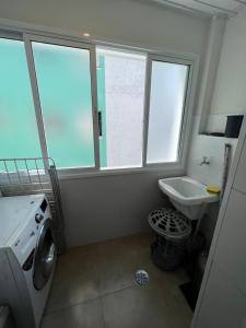 y baño con lavadora y lavamanos. en APTO ENCANTADOR TEMPORADA, en Guarujá