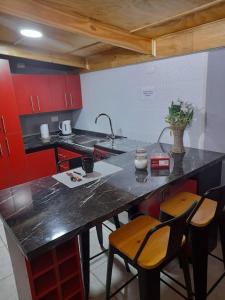 a kitchen with red cabinets and a black counter top at Departamento con acceso independiente - English spoken in Punta Arenas