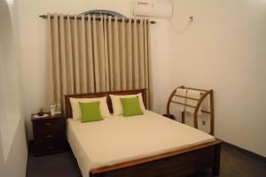 a bedroom with a bed with green pillows and a window at Murphy's Villa in Katunayaka