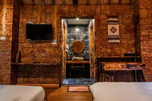 a room with a stone wall with a tv and a bed at Sapa Riverside Ecolodge & Spa in Sa Pa