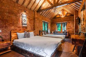 a bedroom with two beds and a brick wall at Sapa Riverside Ecolodge & Spa in Sa Pa
