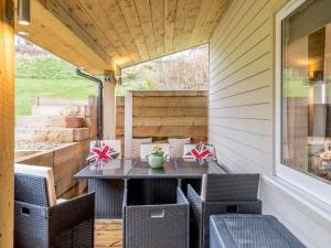 a table and chairs on the back porch of a house at THE HIDEOUT, a Detached Lodge, Hot Tub, Heating, WiFi & Parking in Long Bredy