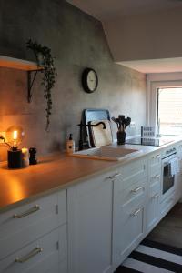 a kitchen counter with a sink and a clock on the wall at NordApart - Butjadingen in Butjadingen