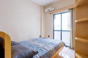 a bedroom with a bed and a large window at Itapema Beira Mar in Itapema