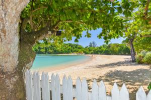 uma cerca branca numa praia com uma árvore e uma estaca branca em Sand and Tan Beach Hotel em Ocho Rios