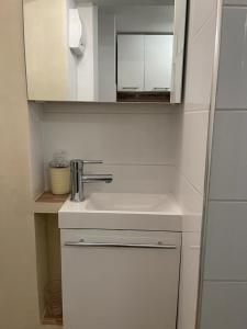 ein weißes Badezimmer mit einem Waschbecken und einem Spiegel in der Unterkunft Mały apartament z kuchnią i łazienką in Stettin