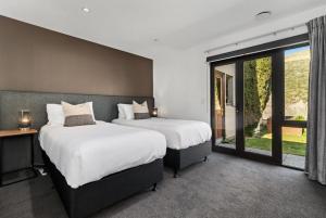 1 dormitorio con 2 camas y ventana grande en Tucker Beach Haven With Spa, en Queenstown