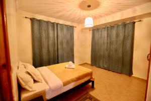 a bedroom with a bed and a window with curtains at Atlantica Ifri Surf Suites in Tamraght Ou Fella