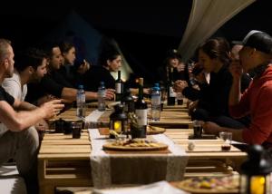 a group of people sitting around a table with bottles of wine at Duna Camp Huacachina in Ica