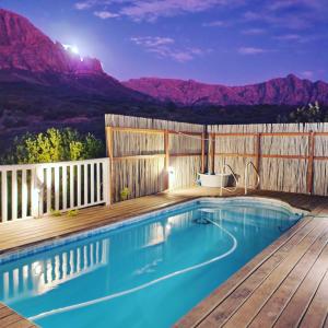 a swimming pool with a wooden deck and mountains at Exquisite chalet on private nature reserve in Wolseley