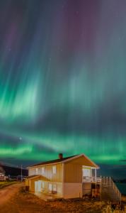 a building with the aurora in the sky at Cozy apartment by the sea in Tromsø