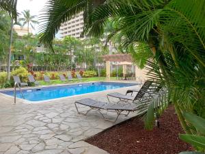 a swimming pool with two lounge chairs next to a resort at Vacation Rental Suites at Royal Garden Waikiki in Honolulu