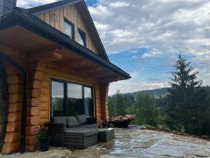 a log cabin with a large window on a patio at MamChwilkeHome in Istebna