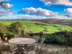 a table and chairs with a view of the rolling hills at Penny Croft - Uk10449 in Llangeinor