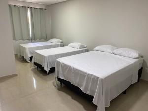 dwa łóżka w pokoju szpitalnym z białą pościelą w obiekcie Hotel Cristalina w mieście Cristalina