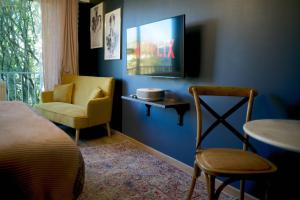 um quarto com uma cama e uma cadeira e uma televisão em Le Boudoir, Centre ville, Parking couvert inclus em Mulhouse