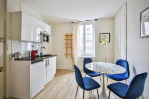 eine Küche mit einem Tisch und blauen Stühlen in einem Zimmer in der Unterkunft 11#Appartement 4Pers#Sèvres-Lecourbe#Necker in Paris