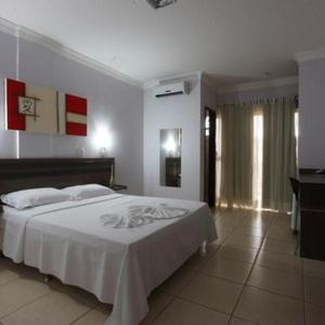 Un dormitorio con una cama blanca y un televisor. en Augustu's Hotel, en Altamira