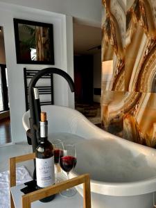 eine Flasche Wein und ein Glas Wein neben einer Badewanne in der Unterkunft ROOF TOP LUXURY in Blagoewgrad