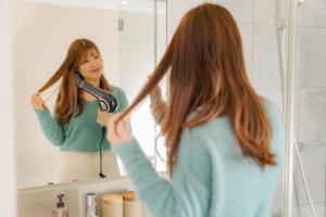 a woman brushing her hair in front of a mirror at OKAYAMA GLAMPING SORANIA - Vacation STAY 19628v in Kurashiki