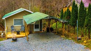 a cabin with a green roof and two chairs at Sky High Cabin in Bryson City in Bryson City
