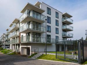 ミエルノにあるMielno Jantaris- Apartament B3- przy plażyのバルコニーとフェンス付きの白いアパートメントです。