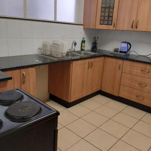 a kitchen with wooden cabinets and a stove top oven at Kennaway Court in East London