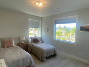 um quarto com 2 camas e uma janela em Big 4 Bd, 4 Ba home, Steps to Ocean with EV Charger em Cowichan Bay