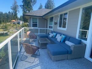 um pátio com um sofá azul e cadeiras numa casa em Big 4 Bd, 4 Ba home, Steps to Ocean with EV Charger em Cowichan Bay