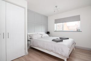 a white bedroom with a bed and a window at 'Modern Living in Old Town Stratford-upon-Avon' in Stratford-upon-Avon