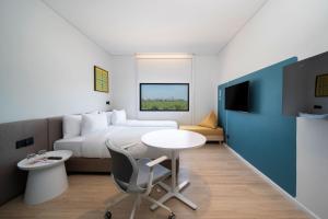 a hotel room with a bed and a table and chair at GO! Hotel Bowin at Robinson Lifestyle Bowin in Si Racha