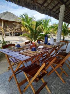 een houten tafel met stoelen en een tafel met eten erop bij Chalé Ibiza in Ponta do Anel