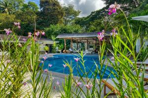 una piscina en un patio con flores en Tribe Boutique Hotel - Adults Only, en Dominical