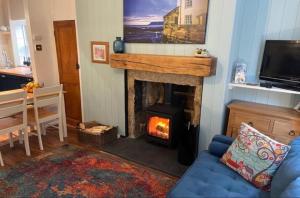a living room with a fireplace and a blue couch at Darnholm Cottage in Robin Hood's Bay