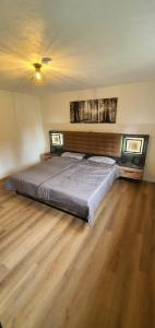 un grande letto in una camera con pavimento in legno di Ferienwohnung Maustadt a Memmingen
