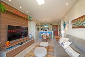 a living room with a couch and a flat screen tv at WaiWai 306 - Apê C/ Varanda Vista Mar by Carpediem in Cumbuco