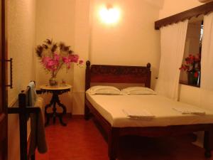 a bedroom with two beds and a table with flowers at Afonso Guest House - Fontainhas in Panaji