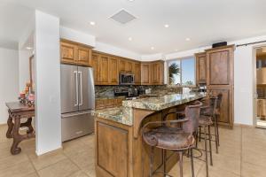 a kitchen with wooden cabinets and a island with bar stools at Bella Sirena 201-C in Puerto Peñasco