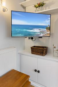 a flat screen tv hanging on a wall in a living room at Dillywicks by Staytor Accommodation in Exeter