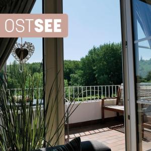 Une porte ouverte s'ouvre sur un balcon offrant une vue sur la terrasse. dans l'établissement Ostsee, wunderschöne Wohnung mit Meerblick, à Harrislee