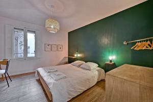 a bedroom with a large bed and a green wall at Aux MARCHES DU PALAIS - AC CLIM - SPACIEUX - TERRASSE - WIFI in Avignon