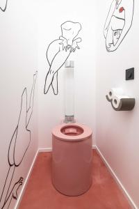 a bathroom with a pink toilet with drawings on the wall at Minamina, chambre avec jacuzzi privatif in Roquefort-la-Bédoule