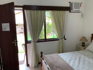 a bedroom with a bed and a large window at Pousada Fazendinha Unamar in Cabo Frio