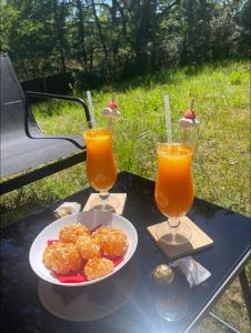 uma mesa com um prato de comida e dois copos de sumo de laranja em Charmant chalet cocooning avec Jacuzzi em Arthon