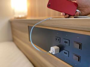 a person holding a red cell phone plugged into a lightswitch at Santiago Hotel - Vacation STAY 74128v in Hiroshima