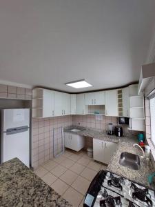 a large kitchen with white cabinets and a sink at dirioma fiori 410 descanso, paz, alegria e muita diversão em águas termais in Caldas Novas